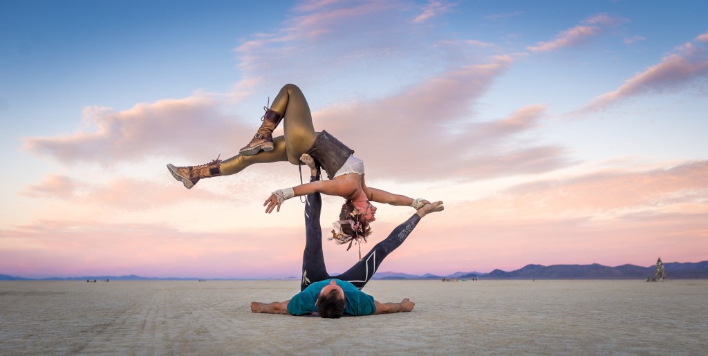 The theme of Acroyoga and Yoga Poses. A pair of two men and a woman stand  in the position of asana. The guy holds the girl arched high back on the out